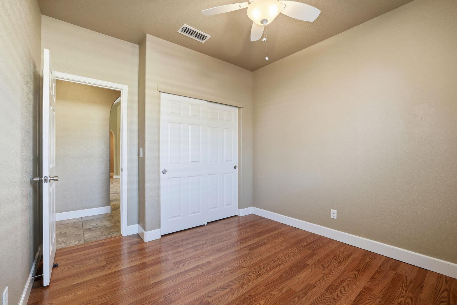 1730 Tasca Lane Manteca, CA 95337 - Photo 32 of 83 an empty room with wooden floor and a ceiling fan