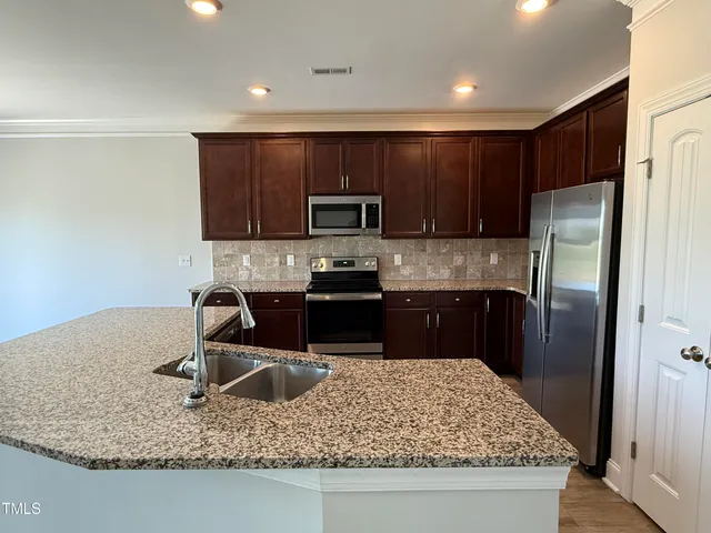a kitchen with kitchen island granite countertop a sink stainless steel appliances and cabinets