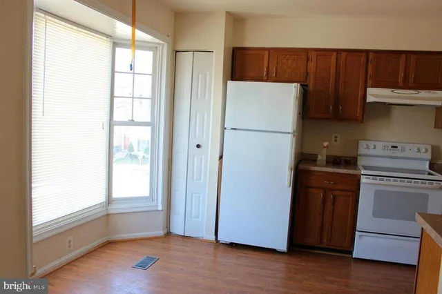 a kitchen with a refrigerator a stove and wooden floor