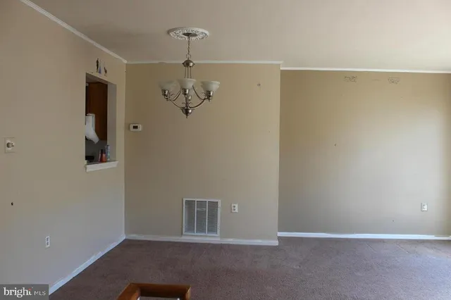 a view of an empty room with chandelier fan
