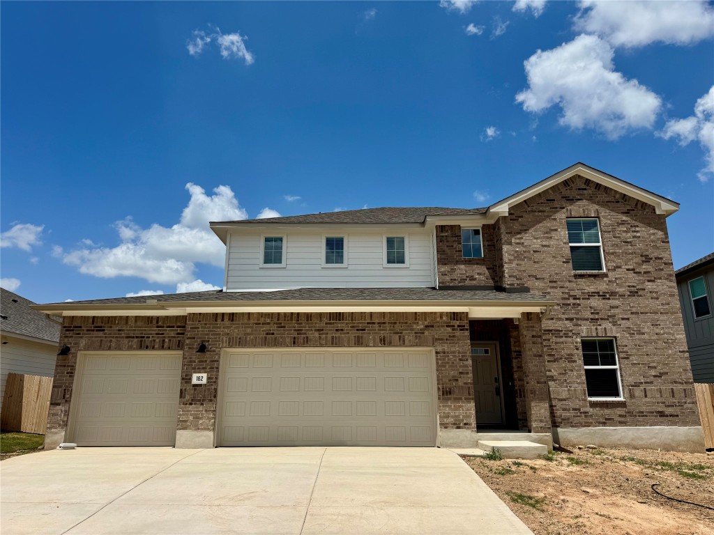 Traditional-style house with concrete driveway, brick siding, and an attached garage