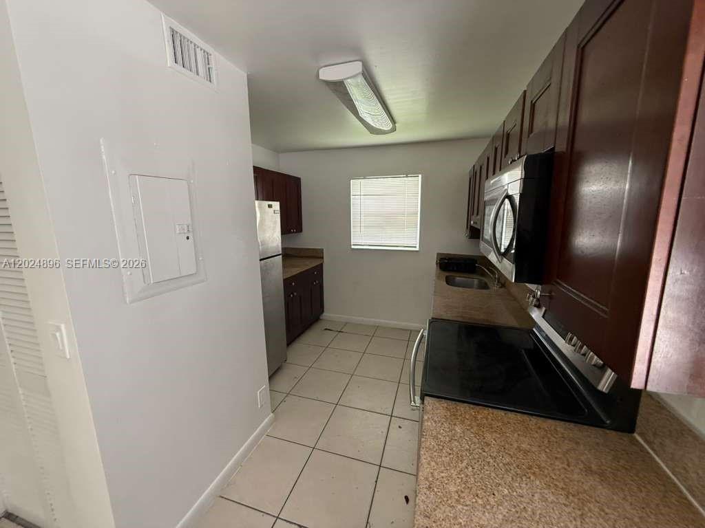 6921 Pembroke Road, Unit 6927 Pembroke Pines, FL 33023 - Photo 5 of 10 a kitchen with granite countertop a refrigerator and a stove