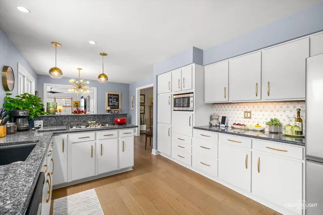 a kitchen with stainless steel appliances granite countertop a stove and white cabinets