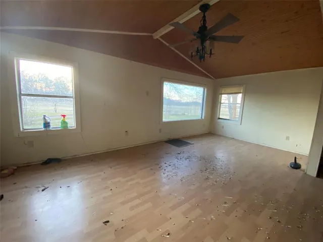 an empty room with windows and ceiling fan