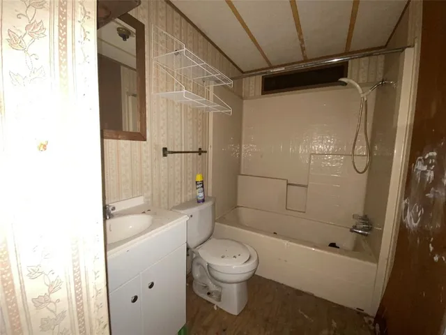a bathroom with a granite countertop bathtub shower sink mirror and toilet