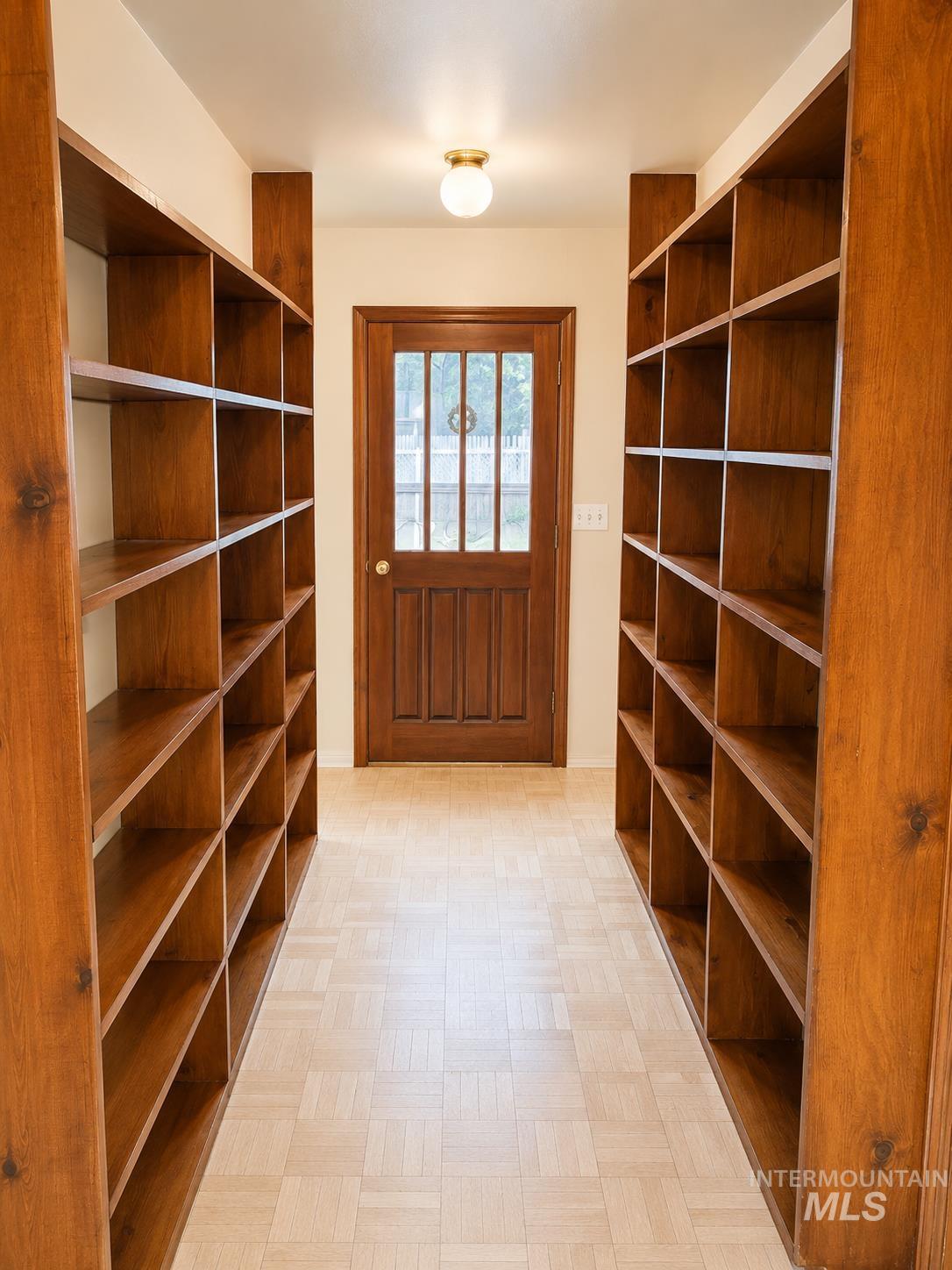 16434 Pride Lane Caldwell, ID 83607 - Photo 10 of 16 Hallway featuring extensive built-in wooden shelving, a paneled door with glass inserts, and a light-toned patterned floor