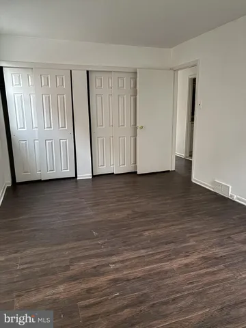 a view of an empty room with wooden floor and closet