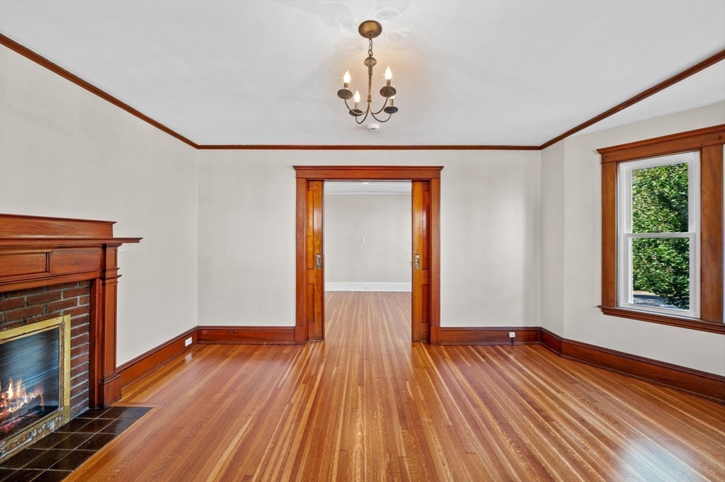 59 Butman Street, Unit 1 Beverly, MA 01915 - Photo 6 of 42 a view of an empty room with wooden floor fireplace and a window