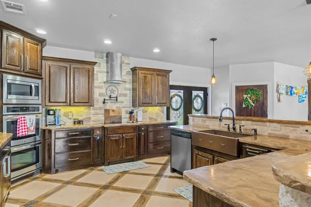 a kitchen with stainless steel appliances granite countertop a sink a stove and a wooden floors