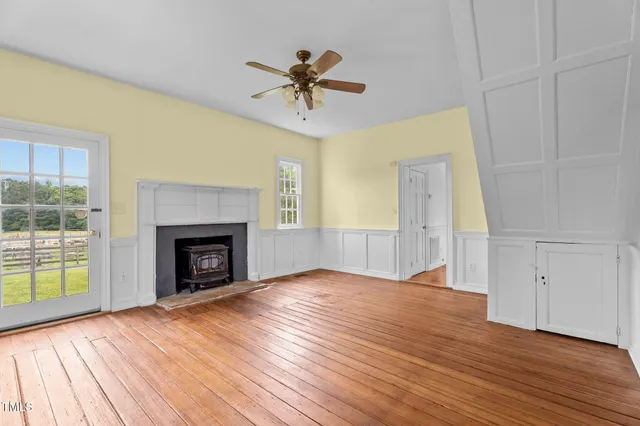 an empty room with wooden floor fireplace and windows