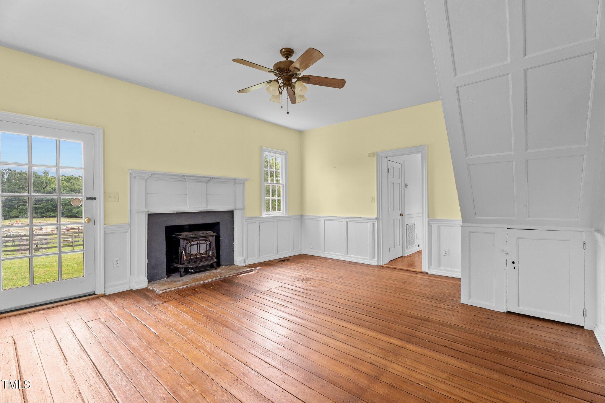 7404 Halifax Road Zebulon, NC 27597 - Photo 11 of 39 an empty room with wooden floor fireplace and windows