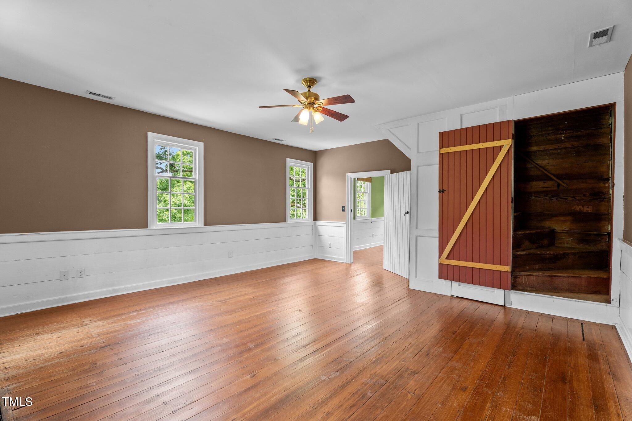 7404 Halifax Road Zebulon, NC 27597 - Photo 29 of 39 an empty room with wooden floor chandelier fan and windows