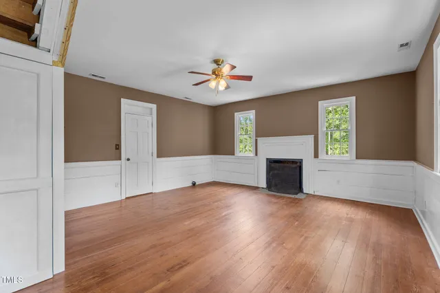 a view of an empty room with window and wooden floor