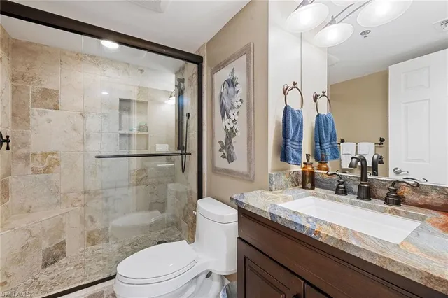 a bathroom with a granite countertop sink a toilet a mirror and shower