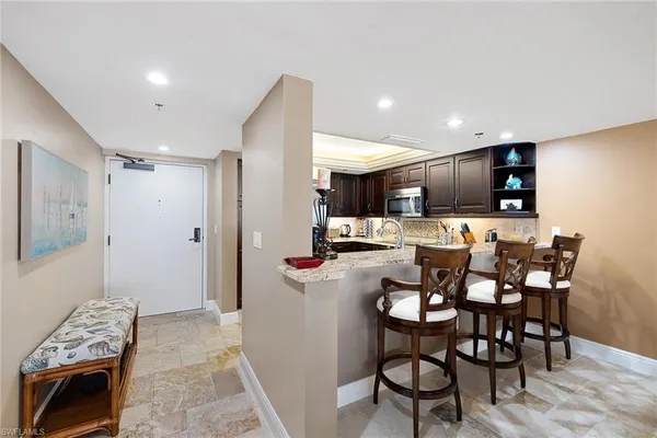 a kitchen with kitchen island granite countertop a sink and a refrigerator