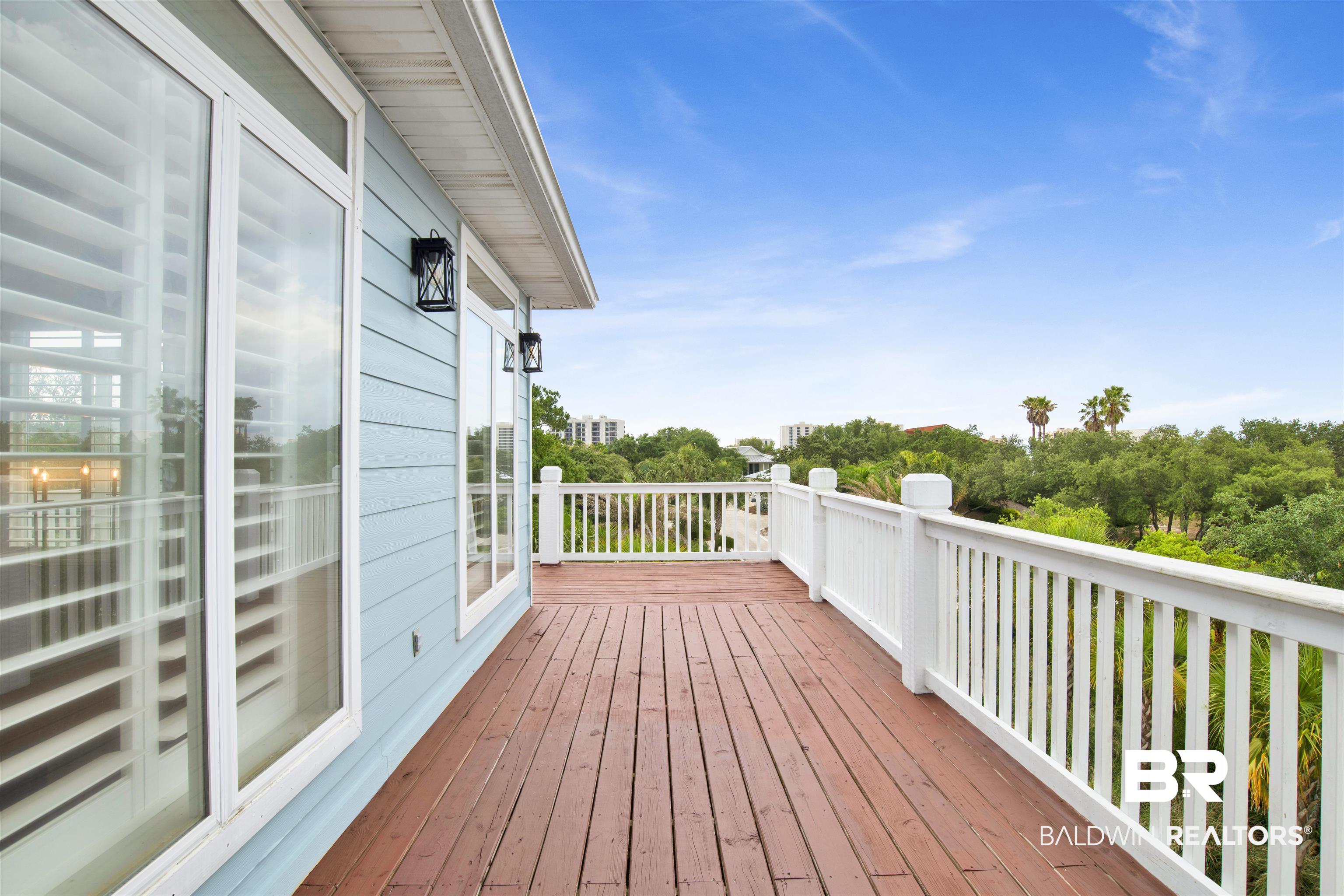 30351 River Road Orange Beach, AL 36561 - Photo 18 of 44 Spacious elevated outdoor deck featuring wood-finish flooring, white railing, and exterior wall lanterns