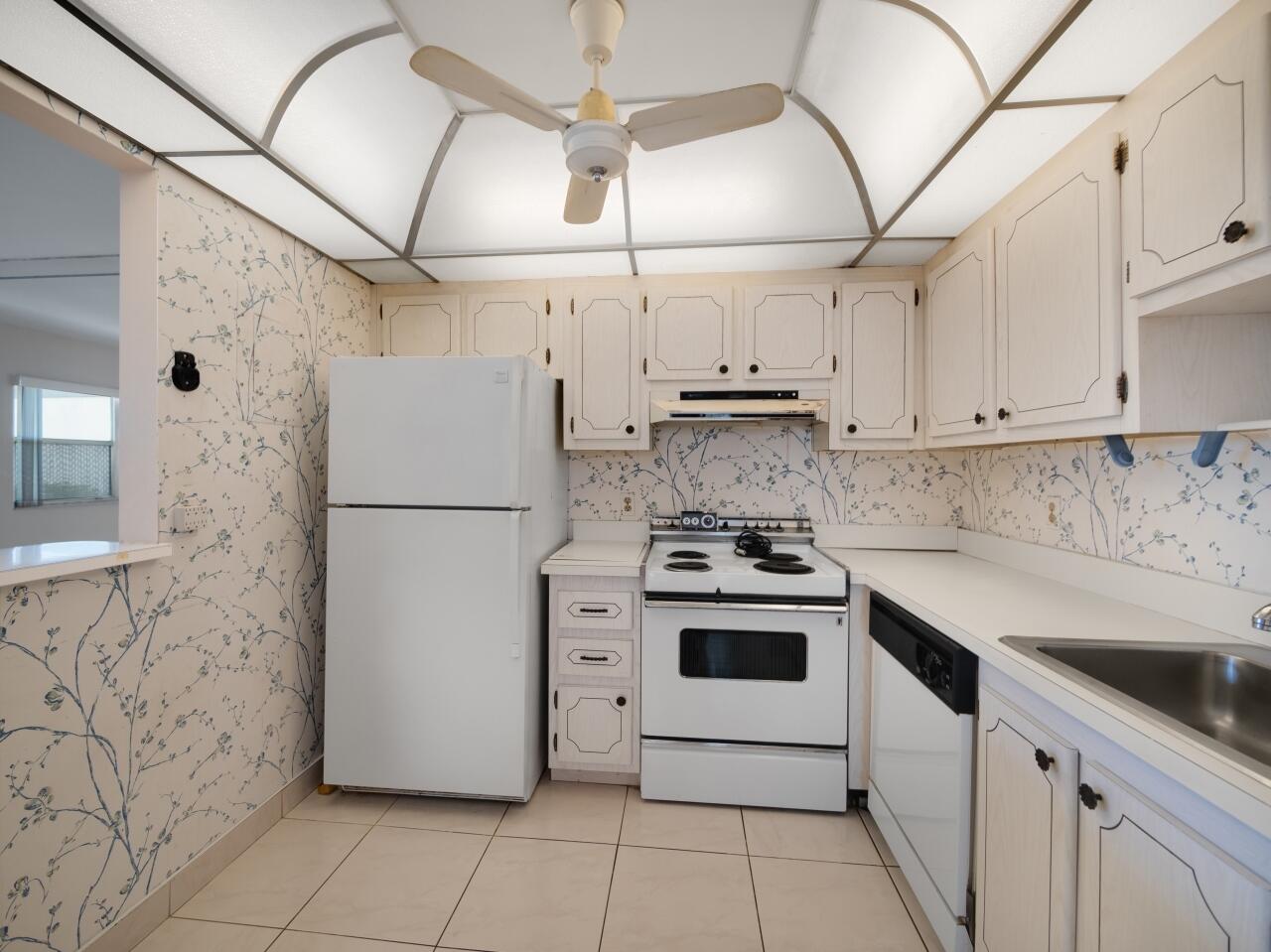 438 Monaco J Delray Beach, FL 33446 - Photo 13 of 15 a kitchen with stainless steel appliances granite countertop a refrigerator sink and white cabinets