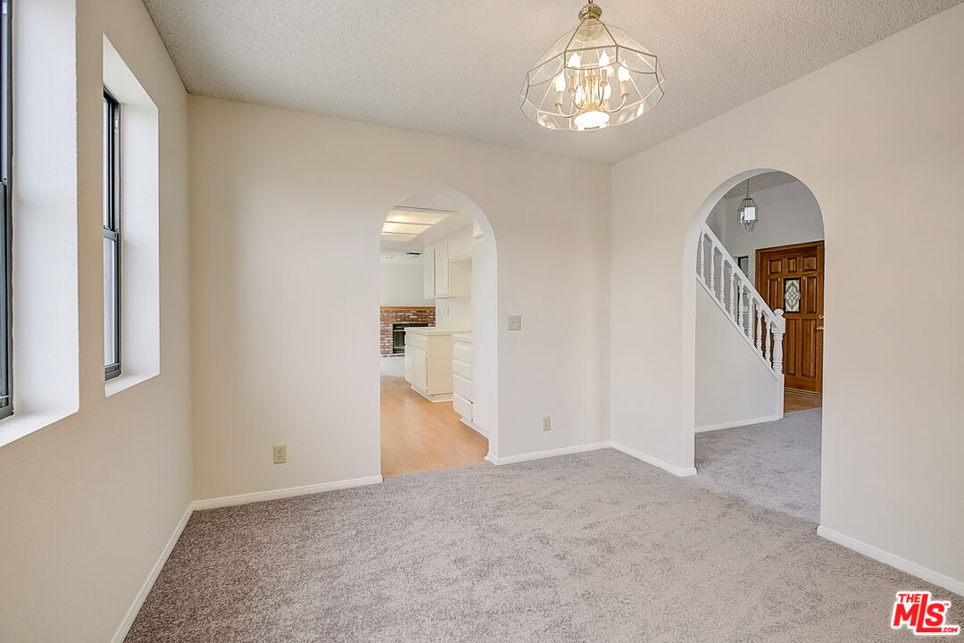 2535 West Ave K9 Lancaster, CA 93536 - Photo 14 of 35 en empty room with chandelier fan and kitchen view