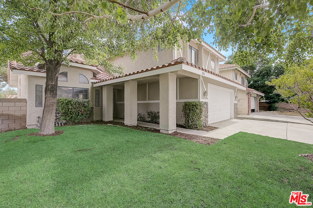 2535 West Ave K9 Lancaster, CA 93536 - Photo 10 of 35 a white house that has a small yard and large trees