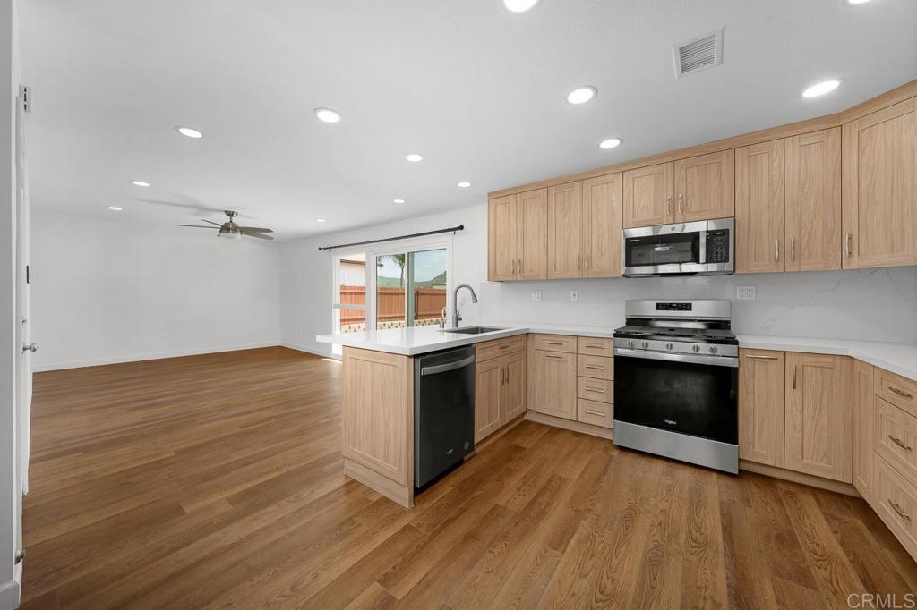 10315 Molino Road Santee, CA 92071 - Photo 6 of 19 a kitchen with granite countertop a stove top oven a sink dishwasher and a microwave oven with wooden floor