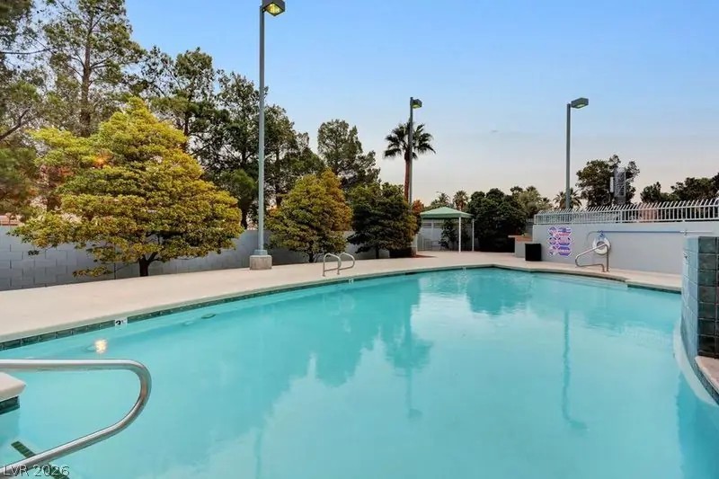 360 East Desert Inn Road, Unit 507 Las Vegas, NV 89109 - Photo 30 of 37 Mature trees and paved decking surround a refreshing community swimming pool under open blue skies.