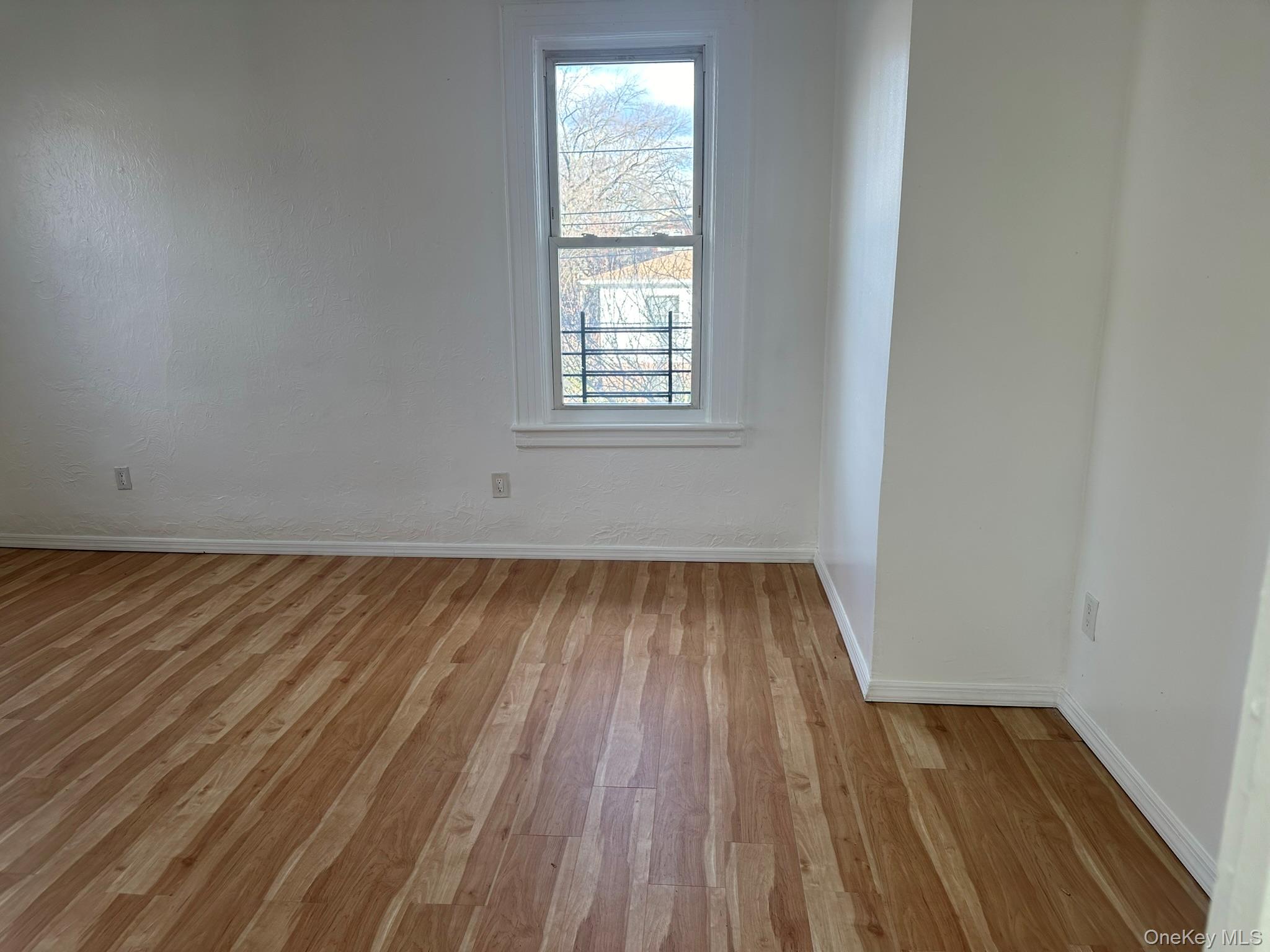 85-20 85th Road Queens, NY 11421 - Photo 6 of 18 an empty room with wooden floor and windows