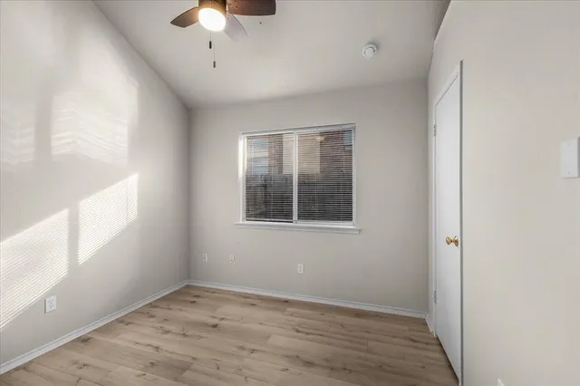 a view of an empty room with a window and wooden floor
