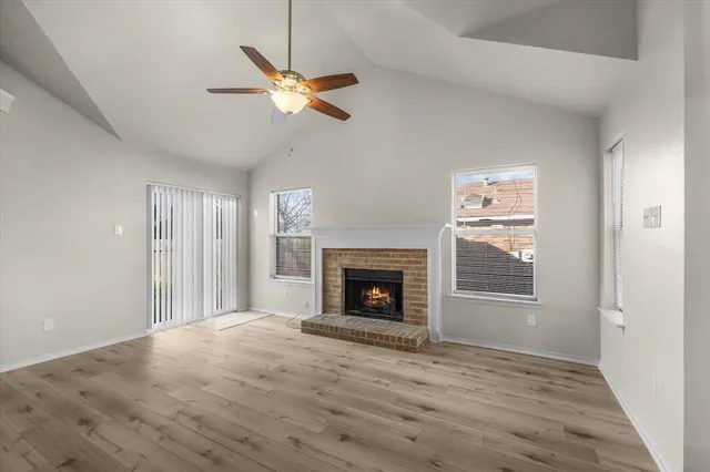 an empty room with windows fireplace and fan