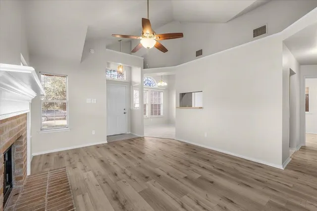 a view of an empty room with a window and wooden floor