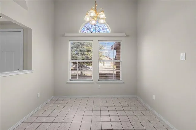 an empty room with windows and chandelier fan