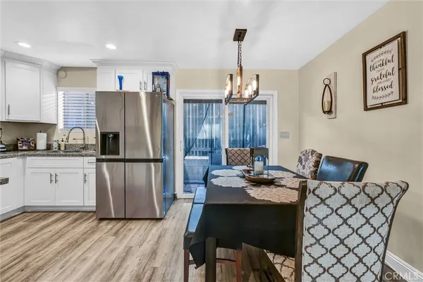a kitchen with stainless steel appliances granite countertop a refrigerator a stove a sink dishwasher a dining table and chairs with wooden floor
