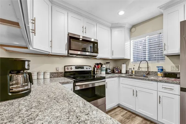 a kitchen with granite countertop a sink a stove and cabinets