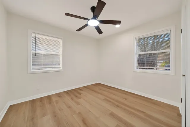 a view of empty room with wooden floor and ceiling fan