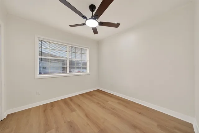 an empty room with a window and ceiling fan