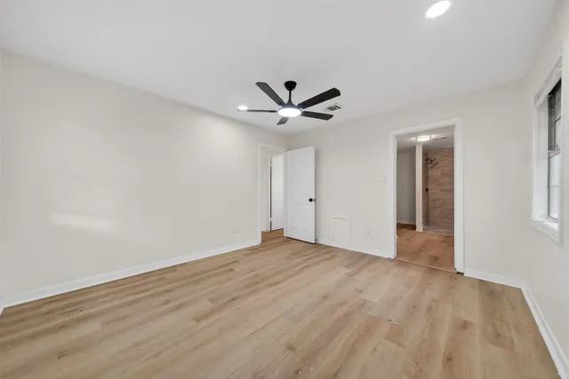 a view of an empty room with cabinet and a ceiling fan