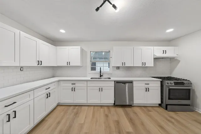 a kitchen with white cabinets appliances and a sink