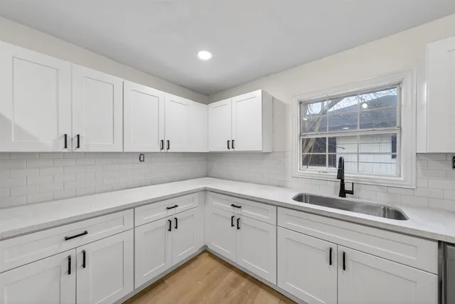 a kitchen with white cabinets sink and window