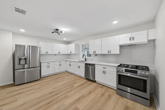 a kitchen with stainless steel appliances granite countertop a stove a sink and a refrigerator