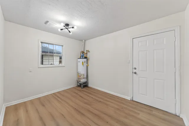 an empty room with wooden floor chandelier and windows