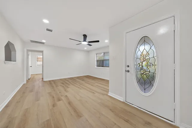 a view of empty room with wooden floor and fan