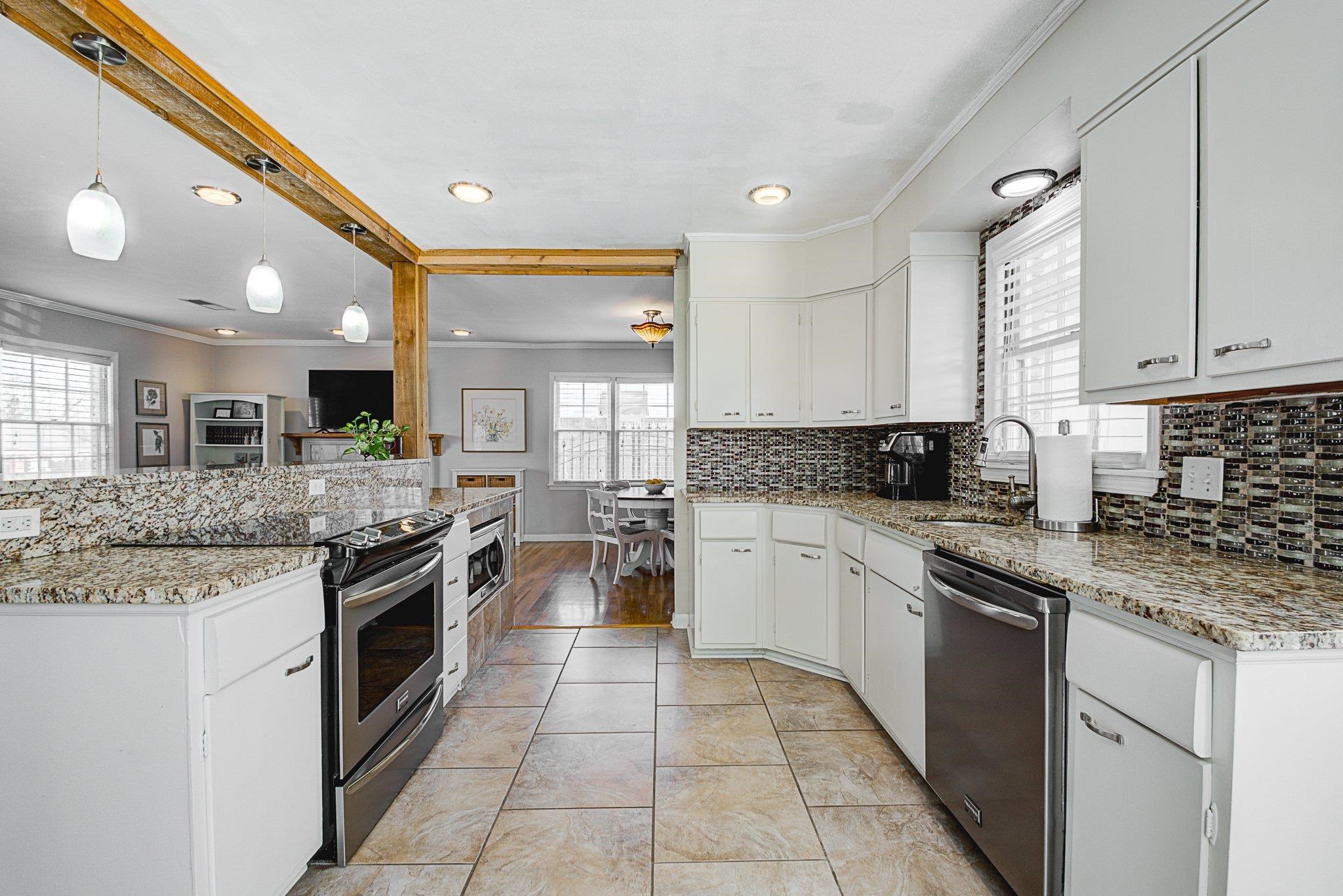 5661 Barfield Road Memphis, TN 38120 - Photo 11 of 31 Kitchen with hanging light fixtures, stainless steel appliances, white cabinets, light tile patterned flooring, and sink