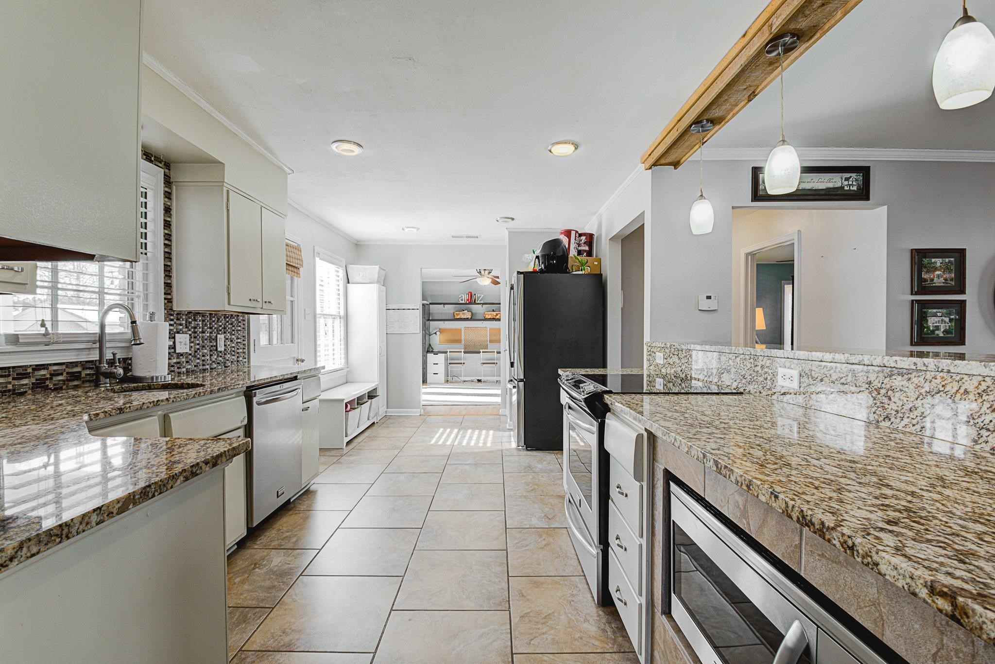 5661 Barfield Road Memphis, TN 38120 - Photo 10 of 31 Kitchen with appliances with stainless steel finishes, stone countertops, white cabinetry, and decorative light fixtures