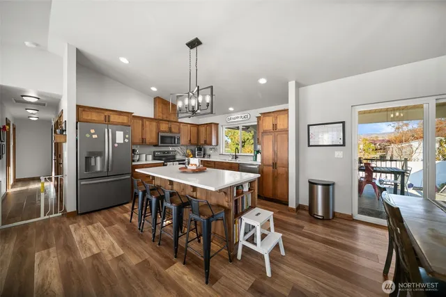 a kitchen with stainless steel appliances a dining table chairs stove and refrigerator