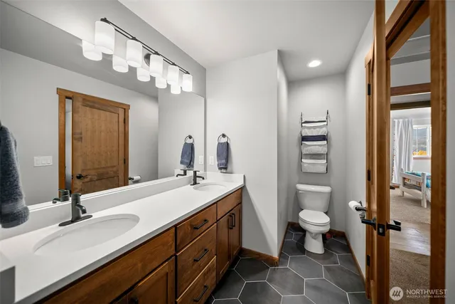 a bathroom with a double vanity sink a mirror and a toilet