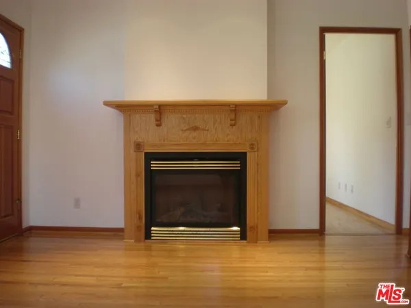 a view of an empty room with wooden floor and a fireplace