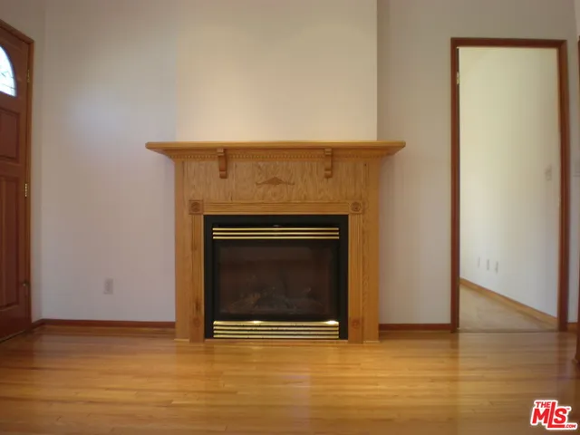 a view of an empty room with wooden floor and a fireplace