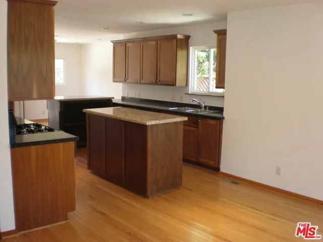 a kitchen with granite countertop a refrigerator and a stove top oven