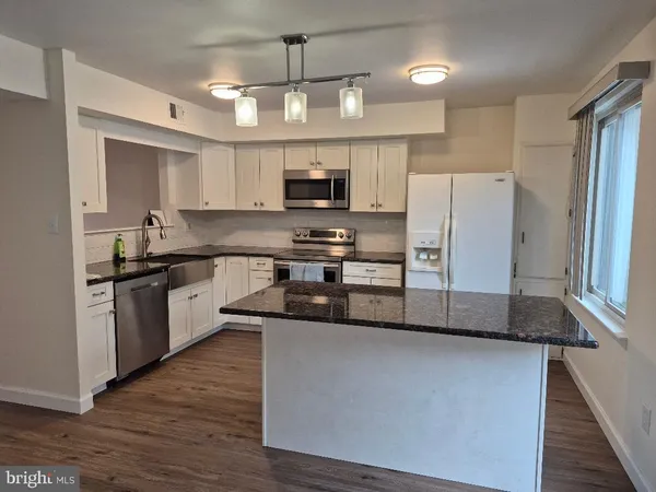 a kitchen with stainless steel appliances granite countertop a refrigerator a sink a stove a microwave and wooden floors
