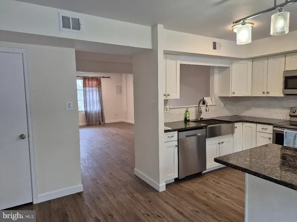 a kitchen with granite countertop wooden floors and white stainless steel appliances