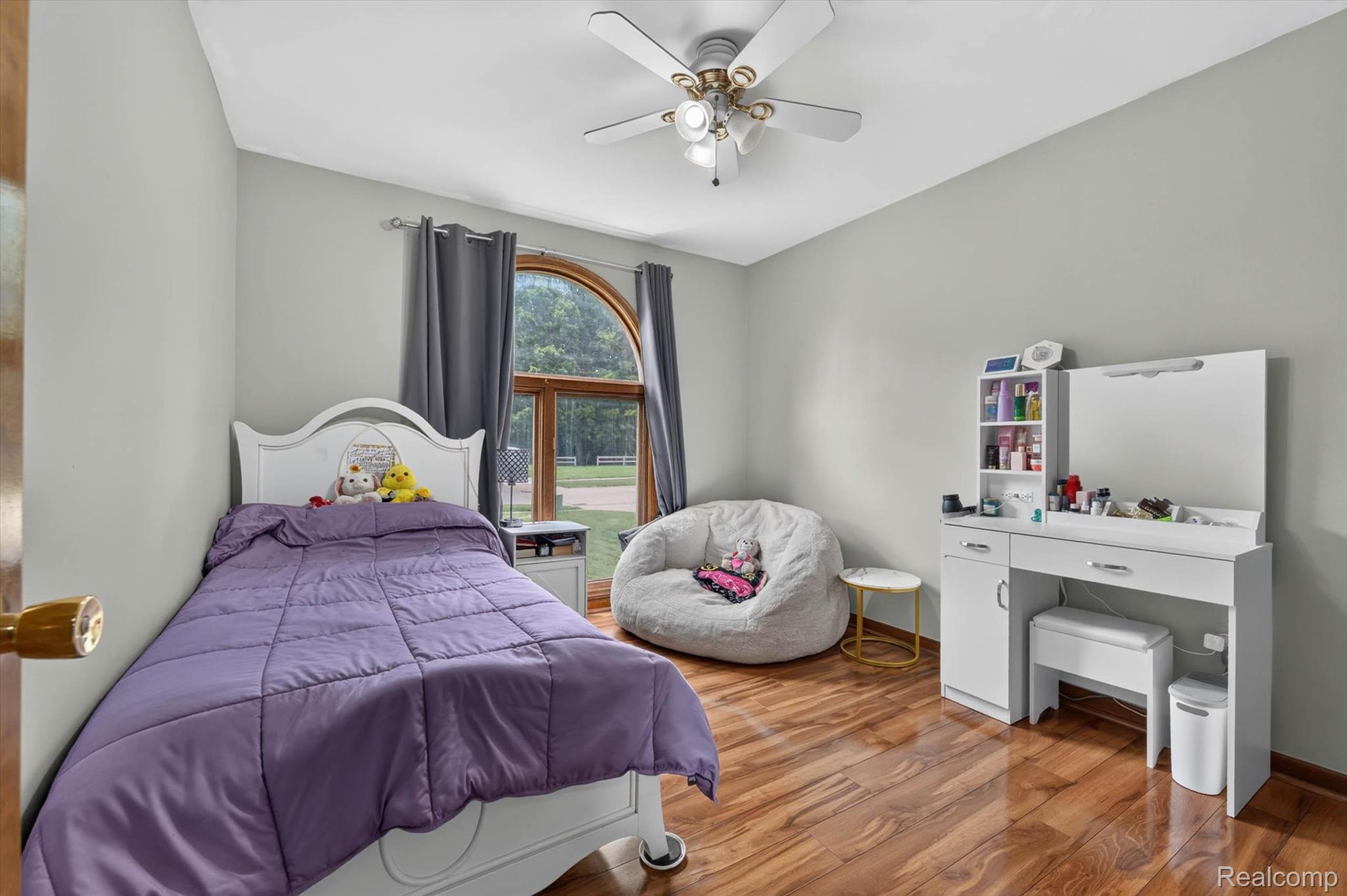 46362 Springhill Drive Utica, MI 48317 - Photo 24 of 59 Arched window with wood frame, wood-finish flooring, ceiling fan with integrated lighting, light gray wall paint, and white trim